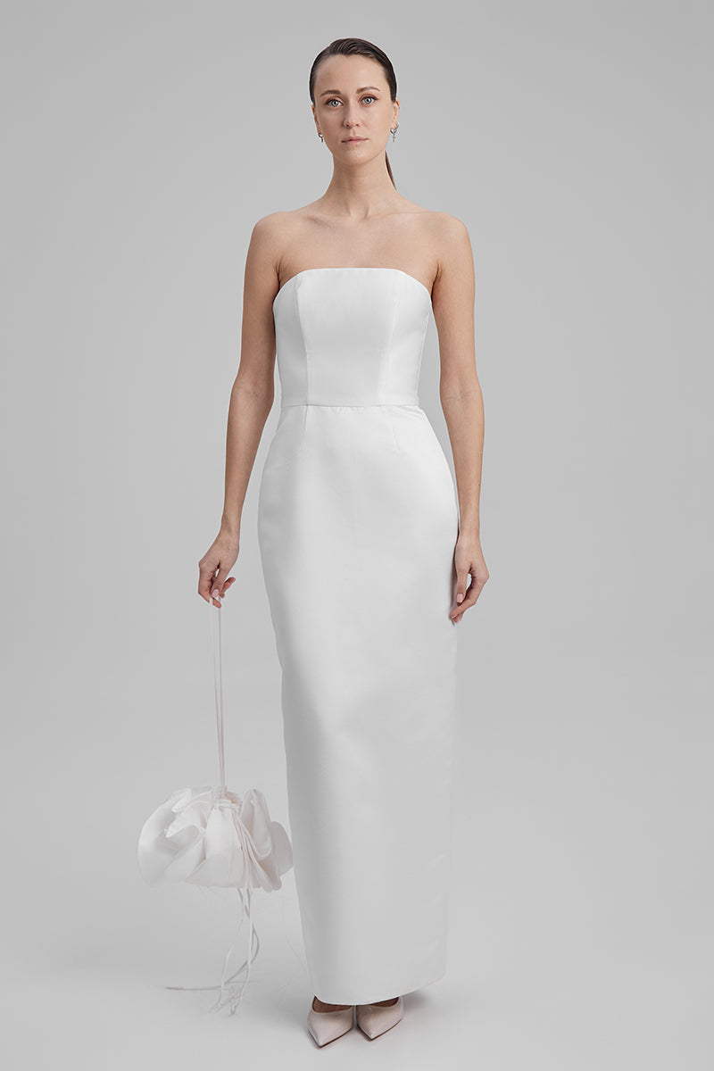 White BAÉ GIGI maxi dress with shoulder bow, flowing fabric, and elegant design, perfect for formal or summer occasions.