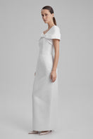 White BAÉ GIGI maxi dress with shoulder bow, flowing fabric, and elegant design perfect for summer or special occasions.