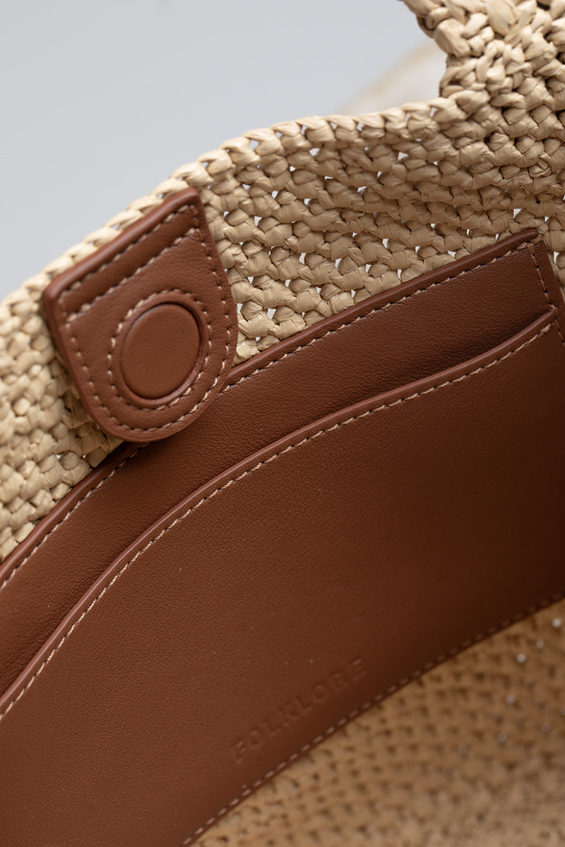 Beige raffia basket bag with top handle from Folklore The Label, ideal for casual or summer outings.
