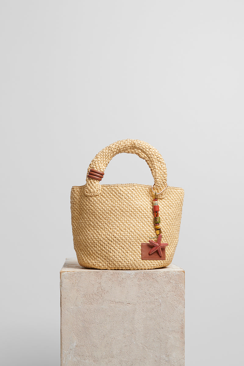 Beige raffia basket bag with top handle from Folklore The Label, stylish and spacious for casual outings.