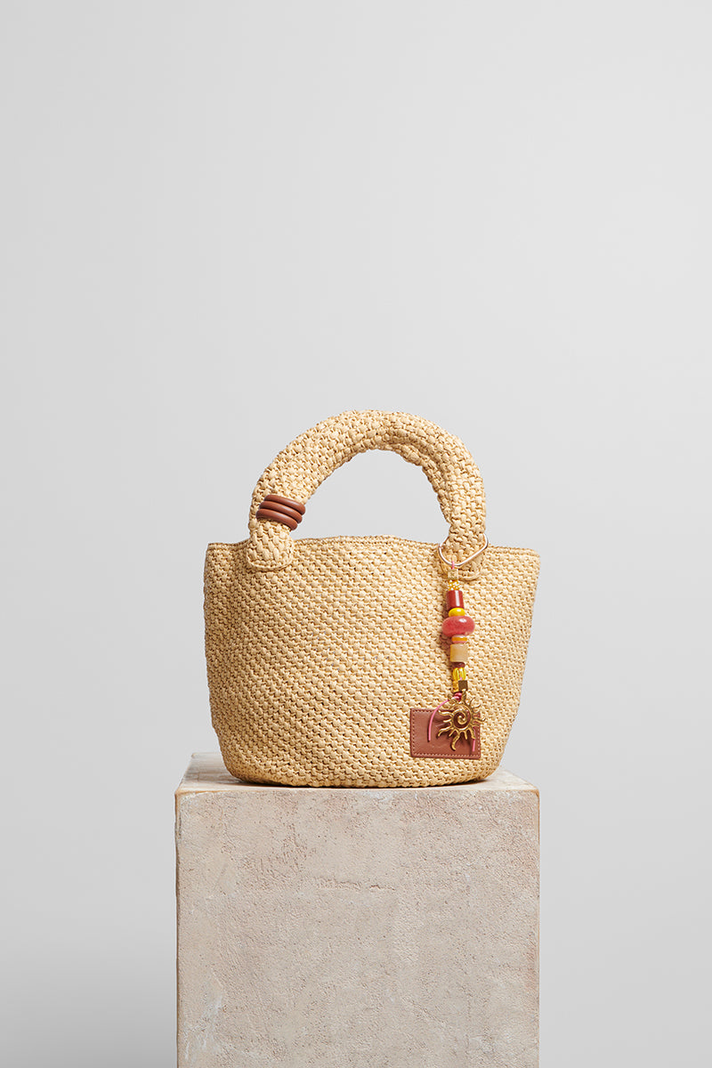 Beige raffia basket bag with top handle from FOLKLORE THE LABEL, natural woven texture, ideal for casual and summer outings.