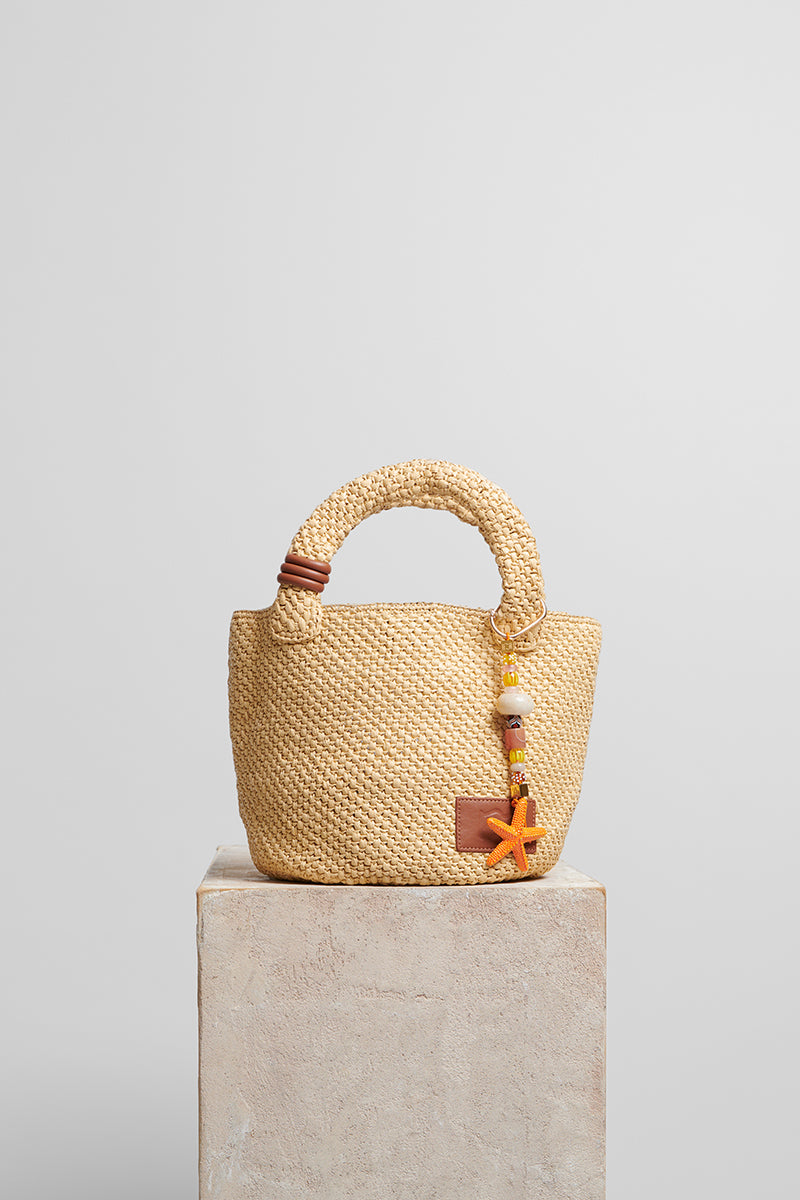 Beige raffia basket bag with top handle from Folklore The Label, perfect for casual and summer outings.