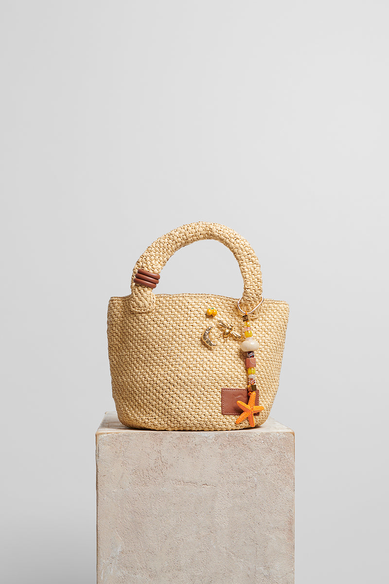 Beige raffia basket bag with top handle from Folklore The Label, perfect for casual and summer outings.