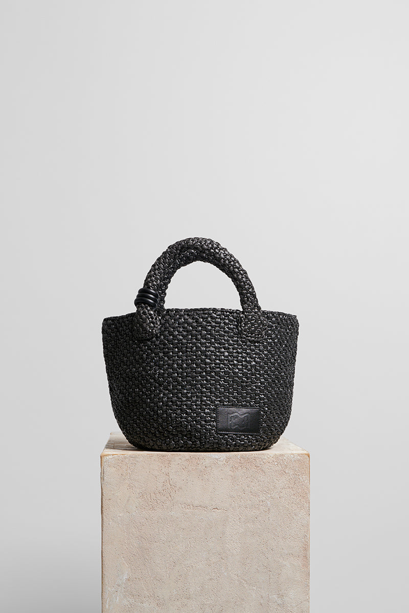 Black raffia basket bag with top handle from FolkLore The Label, featuring a woven design perfect for casual and stylish outings.