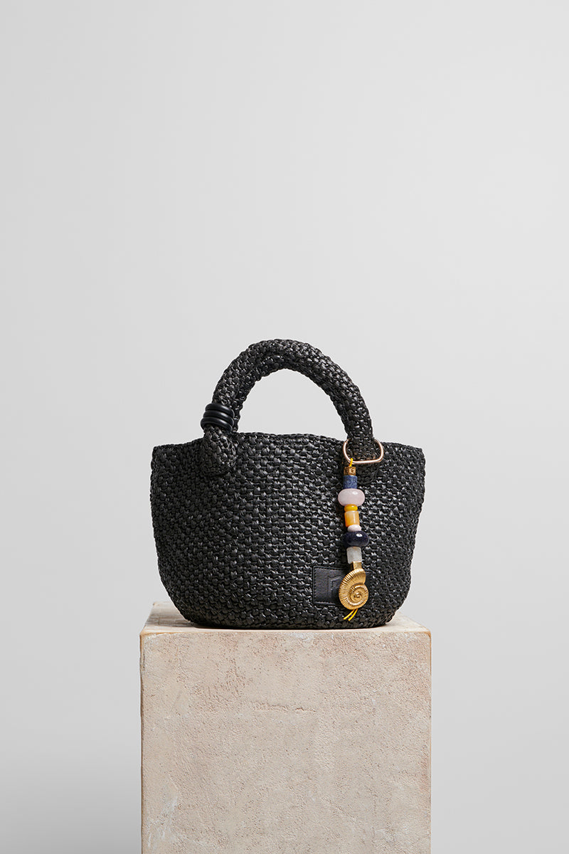 Black raffia basket-style top handle bag by Folklore The Label, featuring a woven woven texture and structured design.