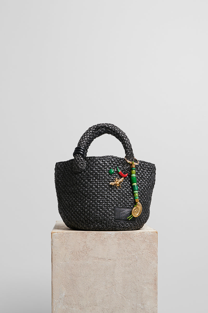 Black raffia basket bag with top handle from Folklore The Label, showcasing a stylish woven design perfect for casual outings.