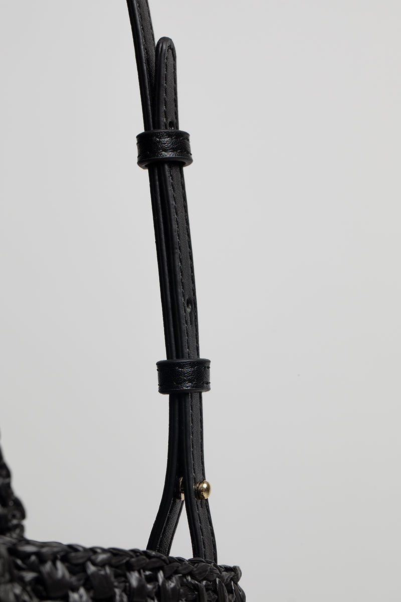 Black raffia basket bag with top handle from Folklore The Label, showcasing its woven texture and stylish design.