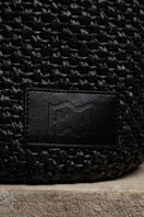 Black raffia basket bag with top handle from Folklore The Label, showcasing a stylish woven design.