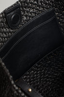 Black raffia basket bag with top handle from FolkLore The Label, featuring a woven design and spacious interior.