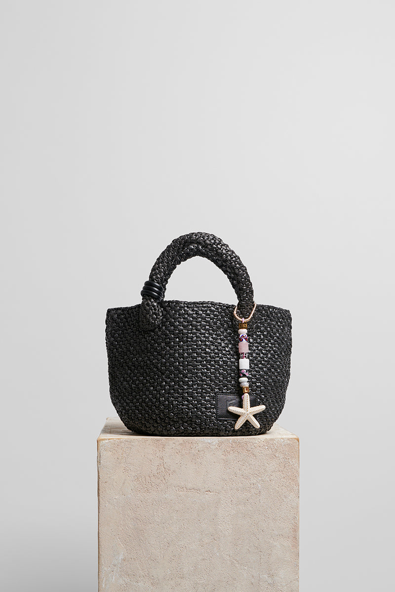 Black raffia basket bag with top handle from Folklore The Label, showcasing a stylish woven design and spacious interior.