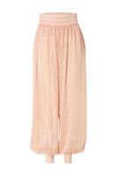 Studio NK Bloom peach pants with a relaxed fit and wide-leg style, shown on a model in a casual outdoor setting.