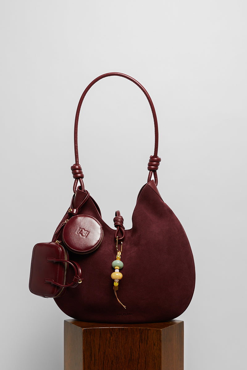 Maroon suede boho shoulder bag by Folklore The Label featuring a relaxed, stylish design with shoulder strap and bohemian details.