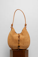 Beige suede boho shoulder bag from Folklore The Label with woven strap and relaxed style.