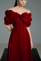 Red off-shoulder velvet gown with petal neckline and A-line silhouette by Happy Clothing, shown on a model.