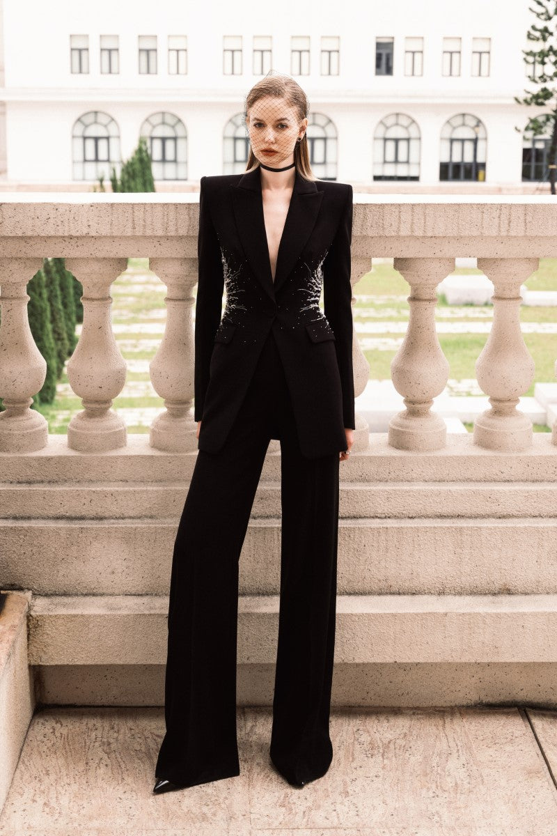 LEKIEU Martine black straight ribbed pants laid flat, showing the fitted waistband and sleek, textured fabric.