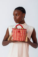 Red Catarina Mina Jirau basket bag with top handle, featuring woven design and stylish craftsmanship.