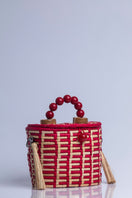 Red Catarina Mina Jirau top handle basket bag with woven design and sturdy handles.