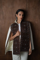 Nadya Shah Balthazar Cape jacket in dark, flowing fabric with wide collar and draped design, displayed on a hanger.