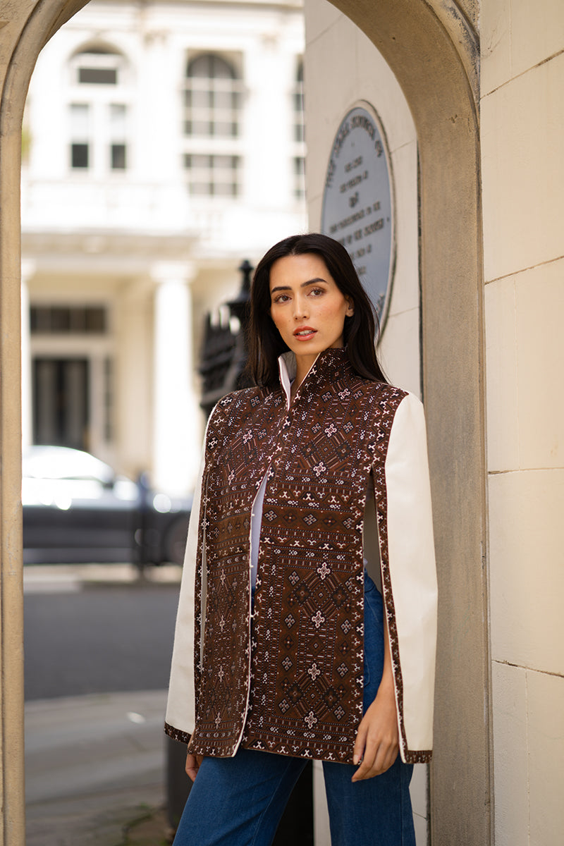 Nadya Shah Balthazar cape jacket in dark fabric, featuring a stylish draped design and elegant collar detail.