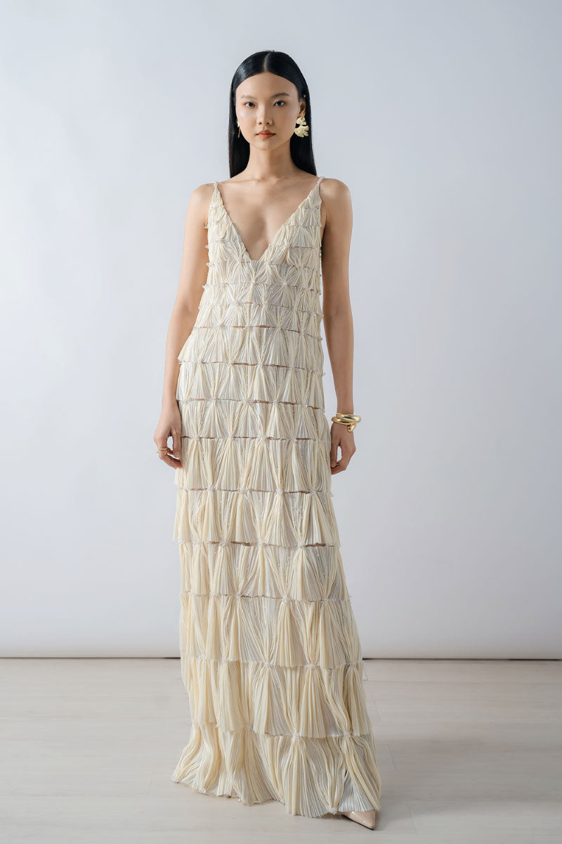 Beige deep V-neck tiered pleated maxi dress by DOC BAN, flowing fabric with layered design and elegant silhouette.