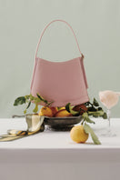 Pink POELLE Bell mini bag with top handle, stylish and compact accessory featuring a sleek design and vibrant color.