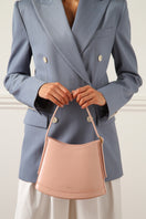 Pink POELLE Bell mini bag with top handle, showcasing its compact design and stylish appearance.