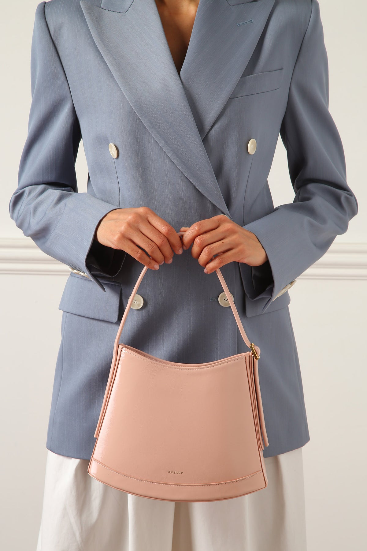 Pink POELLE Bell mini bag with top handle, showcasing its compact design and stylish appearance.