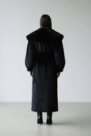 Black faux fur coat by Fortini, stylish old money-inspired design, shown hanging on a hanger with a plush texture.