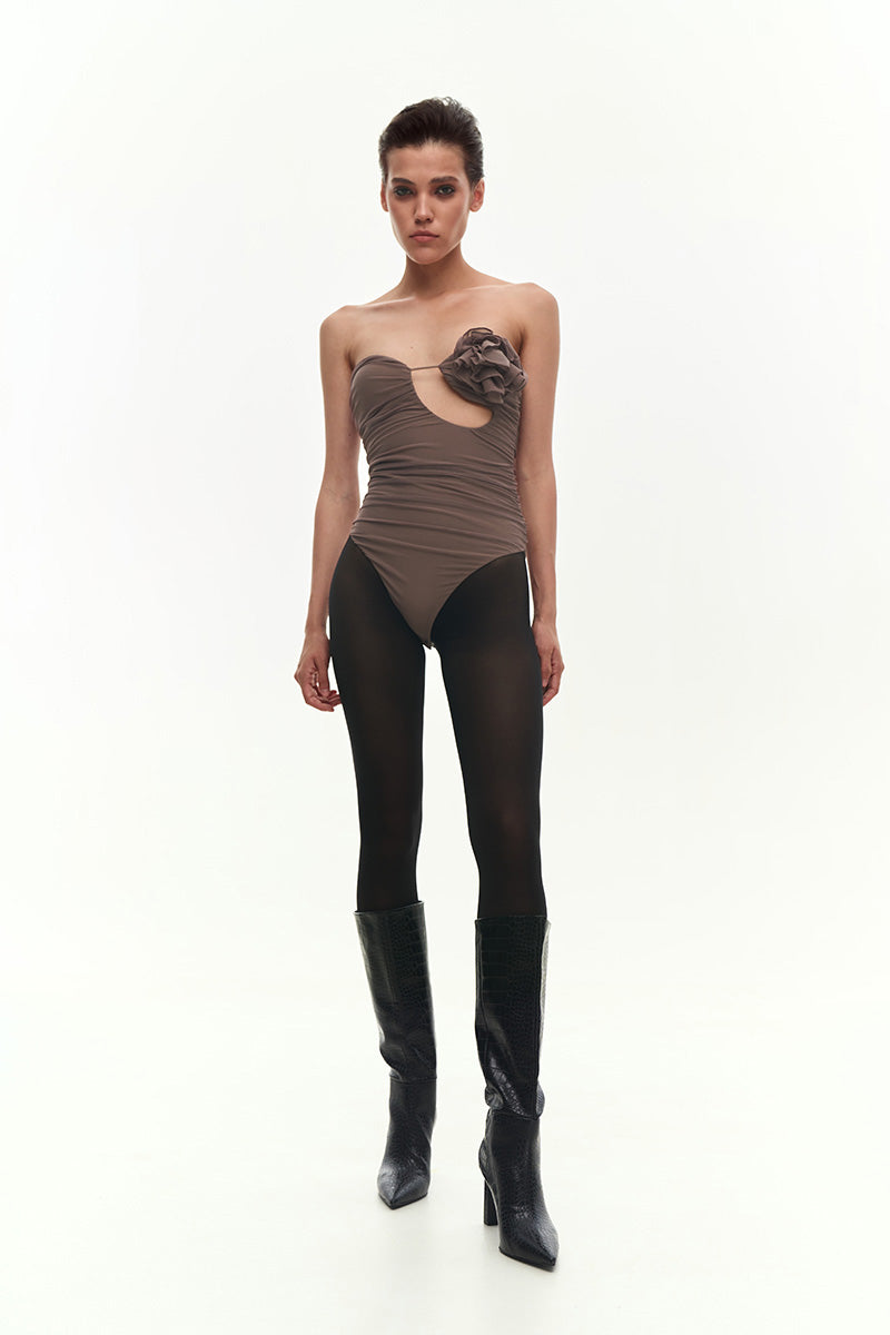 Brown draped bustier bodysuit with flower applique by Kris Marán, featuring a fitted design and elegant detailing.