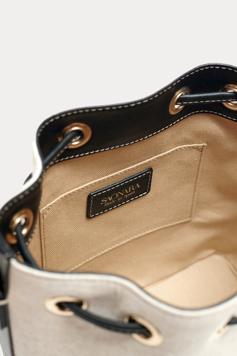Saonara bucket shoulder bag in linen and black leather with a sleek, rounded design and adjustable strap.