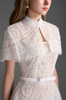 White architectural lace bustier A-line gown with mini cape and crystal embellishments by I.H.F Studio, elegant evening dress.