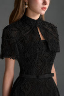 Black architectural lace bustier A-line gown by I.H.F Studio with a mini cape and crystal embellishments.