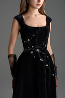 Black Lyon velvet A-line midi gown by I.H.F Studio featuring a sleek silhouette and elegant design, shown on a dress form.
