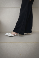 Christin Wu Camelia Cream Bloom Heels shown in a lifestyle image, featuring elegant floral-inspired design and nude color.