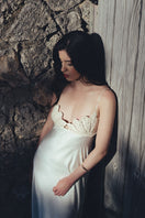 Elegant white concha dress by Maylé Vásquez, featuring flowing fabric and intricate detailing, perfect for formal occasions.