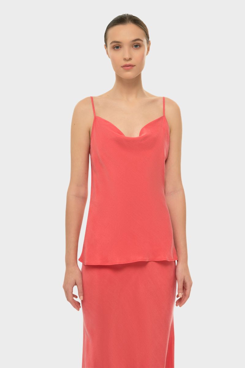 A coral niLuu Aquaflora cowl cami top displayed on a hanger with soft fabric folds and a draped cowl neckline.