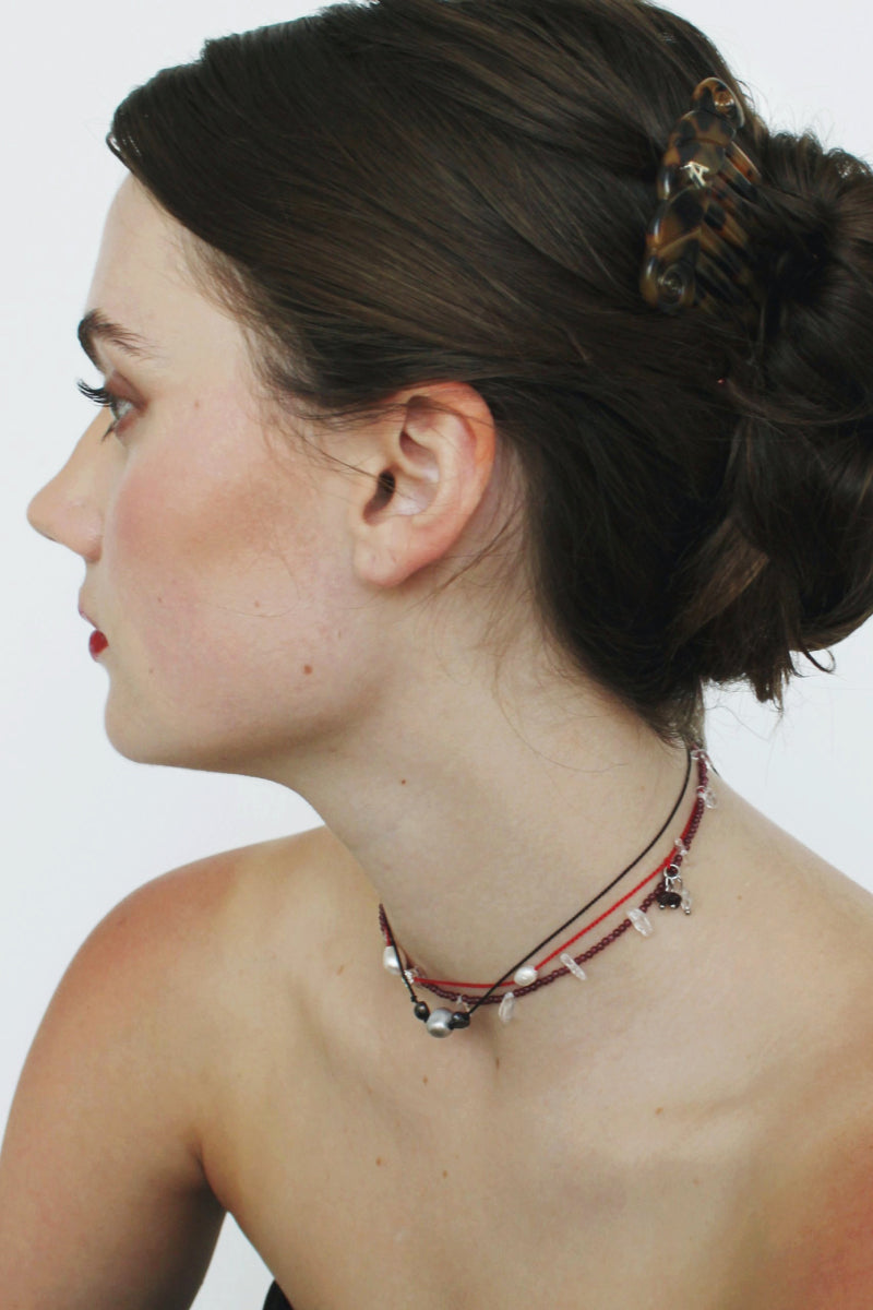 Aethera TUXI Garnet Clear Quartz necklace featuring a red gemstone pendant on a delicate chain.