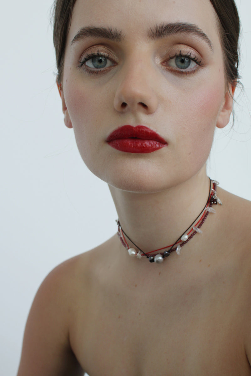 Aethera TUXI Garnet and Clear Quartz necklace featuring a vibrant red gemstone pendant on a delicate chain.
