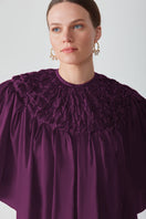 Hand-smocked aubergine cape top by Mastani, featuring intricate detailing and a stylish, flowy design.