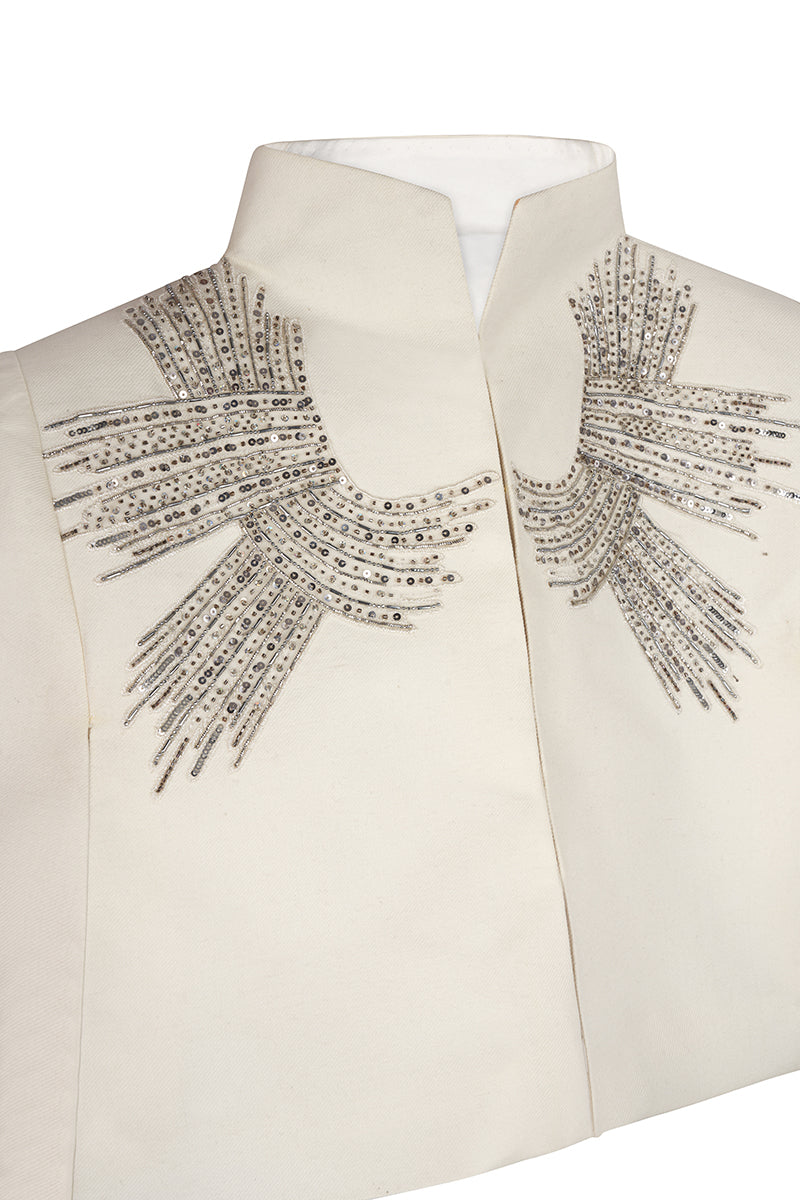 Nadya Shah Cape Eclat Ivory jacket displayed on a hanger, showcasing its elegant design and soft ivory fabric.