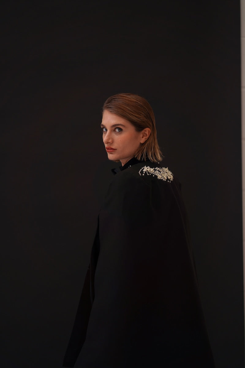 Nadya Shah Cape Nocturne jacket featuring a dark, elegant design with a flowing silhouette and intricate detailing.