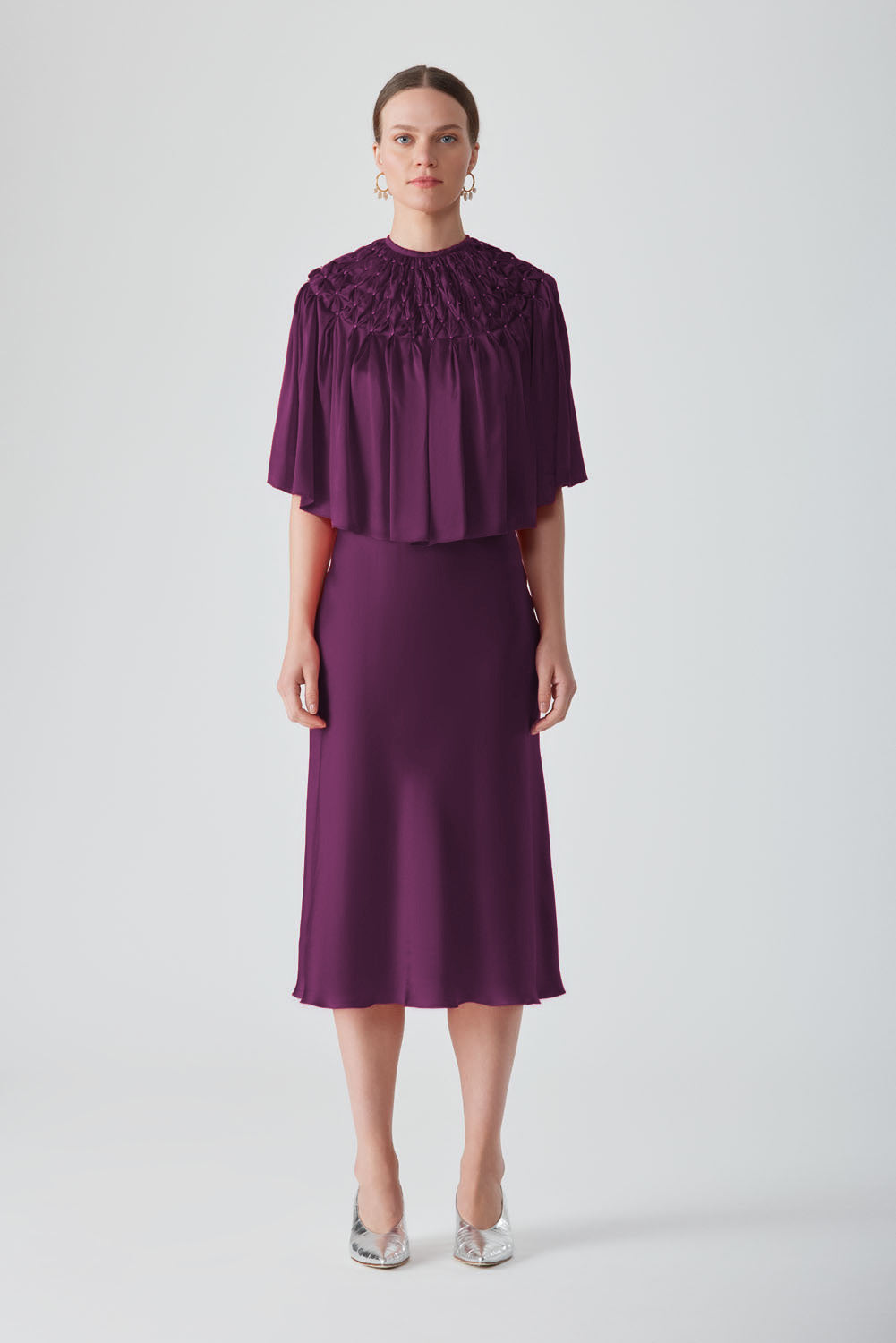 Hand-smocked aubergine cape from MASTANI, a stylish tops piece with intricate detailing and flowing fabric.