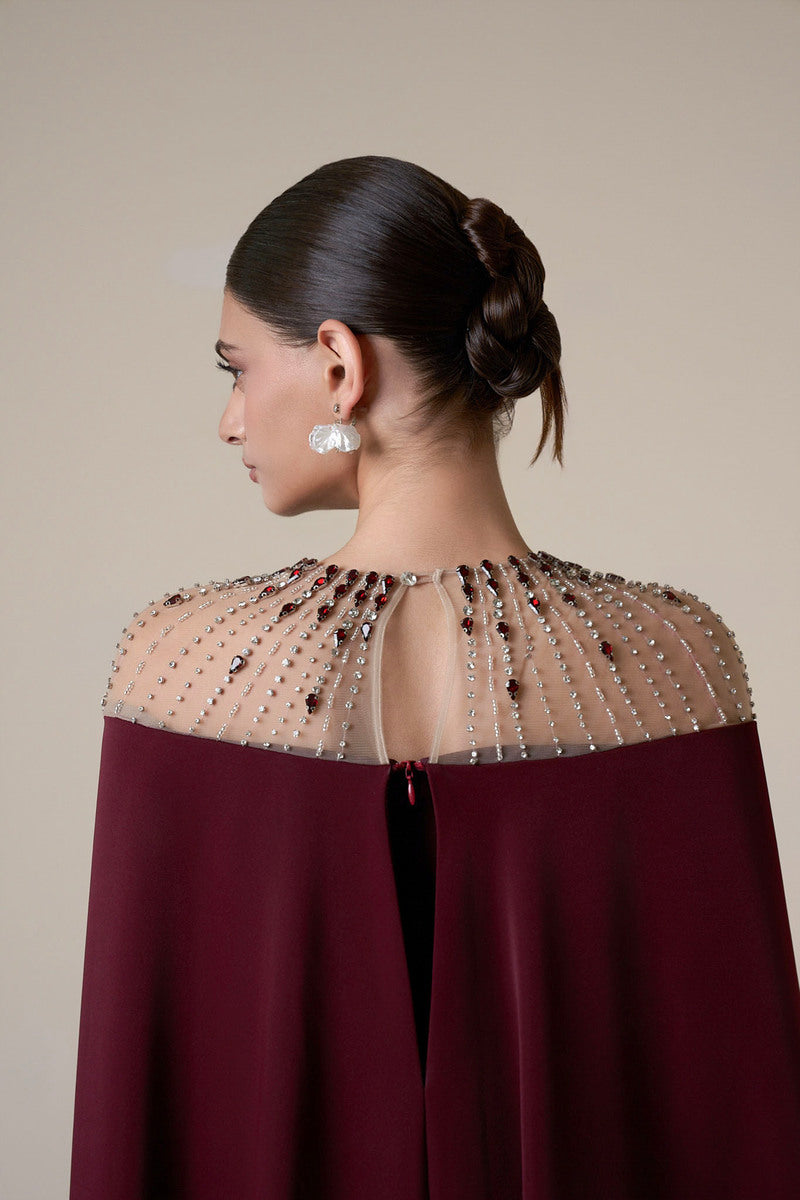 Long burgundy long sleeve gown by HACCHIC COUTURE displayed on a mannequin with elegant draping and a flowing silhouette.