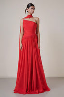 Red pleated gown with a matching cape by HACCHIC COUTURE, showcasing elegant fabric and intricate pleating details.