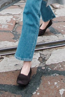 A pair of Carla brown satin flats by AERA with pointed toes and sleek design, displayed on a neutral background.