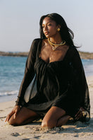 Nana Jacqueline Carmen mini dress in black, off-shoulder style with fitted silhouette and elegant design, shown in a campaign setting.