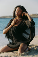 Black Nana Jacqueline Carmen mini dress with off-shoulder design, shown on a model in a fashion campaign image.