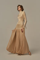 Poem Cascade gown in warm sand color, flowing fabric with elegant drape, modeled on a person showing its full length and stylish design.