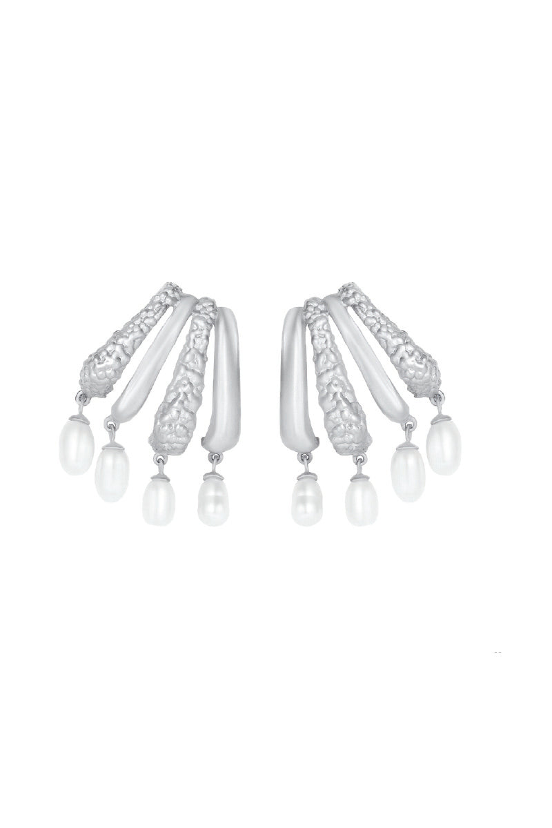 Silver Cassandra earrings by Jude Benhalim with intricate design and shiny rhodium finish, hanging from ear lobes.