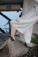 A pair of blue denim AERA Claudia slingback sandals with open toes and ankle straps, displayed on a white background.
